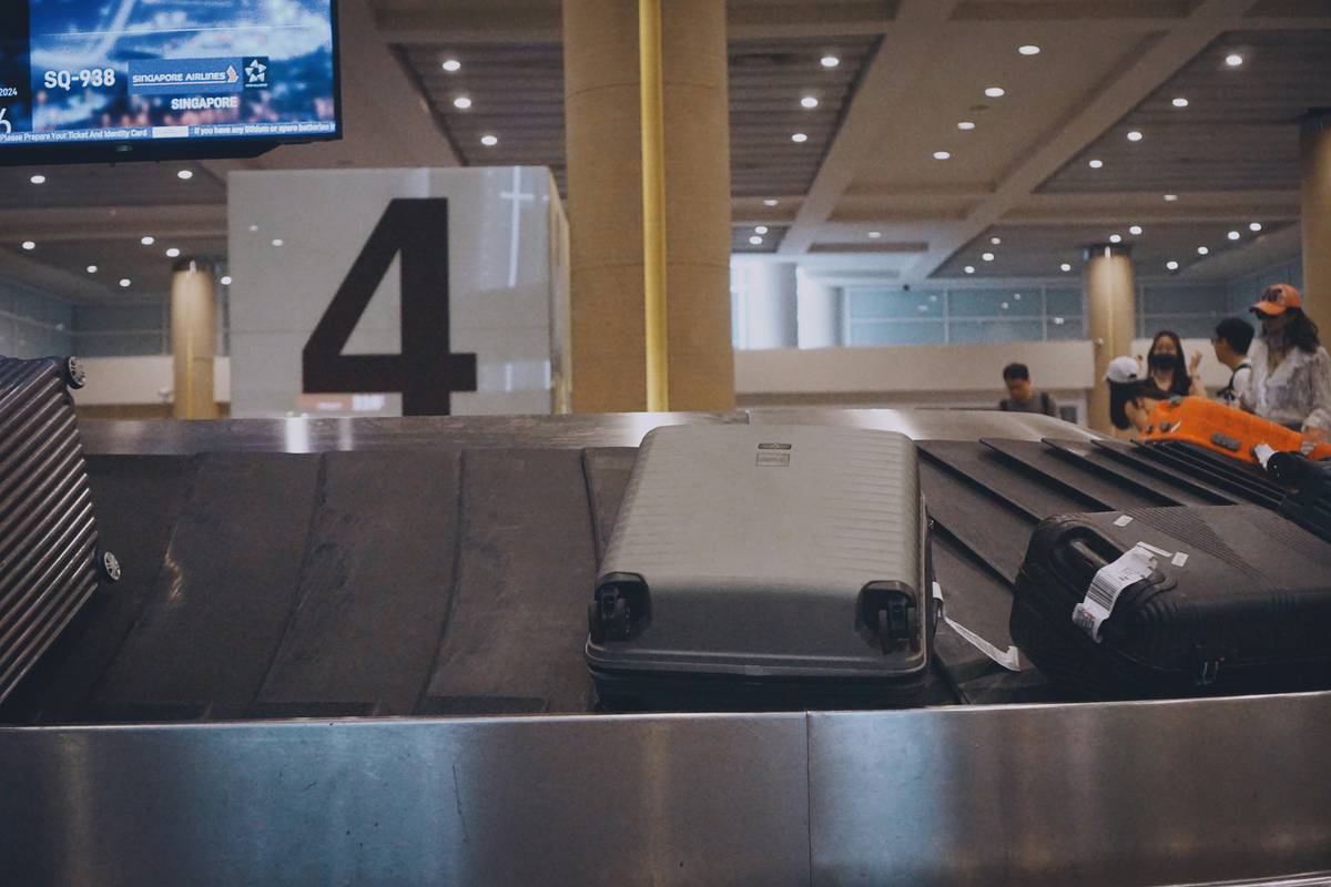 A frustrated traveler sitting on airport floor surrounded by empty baggage tags